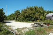 Photo: 020, From the shoreline access the picnic table and fire ring are to the far right. A RV with its awning out is on the site to the right. Buttonwood, sea grape and palm trees grow in the buffer between the sites.
