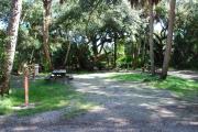 Campsite 3 is a partial sunny site with a gravel foundation located on the right hand side of the road.  Looking into the site on the right is the water and 50amp electrical service. There is a picnic table and ground campfire ring.  At the front left side of the site is the brown site marker.