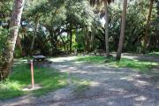 This is a picture of campsite 3 looking from the road into the partly sunny site.  This site has 50amp service and water hookups.  There is a gravel foundation with a picnic table and a ground campfire ring.