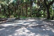 This is a picture of campsite 10 looking from the road into the partly sunny site.  This site has 50amp service and water hookups.  There is a gravel foundation with a picnic table and a ground campfire ring.