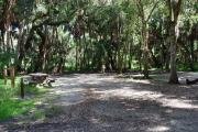 This is a picture of campsite 11 looking from the road into the partly sunny site.  This site has 50amp service and water hookups.  There is a gravel foundation with a picnic table and a ground campfire ring.