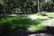 This is a picture of campsite 12 from the back of the site looking toward the road.   The site has water and 50amp electric service.  This is a partly sunny site with a gravel foundation.  The site has a picnic table and a ground campfire ring.