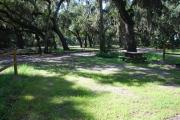 This is a picture of campsite 13 from the back of the site looking toward the road.   The site has water and 50amp electric service.  This is a sunny site with a gravel foundation.  The site has a picnic table and a ground campfire ring.