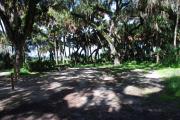 This is a picture of campsite 14 looking from the road into the shady site.  This site has 50amp service and water hookups.  There is a gravel foundation with a picnic table and a ground campfire ring.