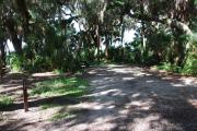 This is a picture of campsite 17 looking from the road into the partly sunny site.  This site has 50amp service and water hookups.  There is a gravel foundation with a picnic table and a ground campfire ring.