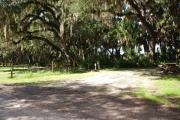 Campsite 18 is a partial sunny site with a gravel foundation located on the right hand side of the road.  Looking into the site on the right is the water and 50amp electrical service. There is a picnic table and ground campfire ring.  At the front left side of the site is the brown site marker.