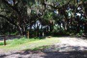 This is a picture of campsite 18 looking from the road into the partly sunny site.  This site has 50amp service and water hookups.  There is a gravel foundation with a picnic table and a ground campfire ring.