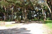 Campsite 21 is a partial sunny site with a gravel foundation located on the right hand side of the road.  Looking into the site on the right is the water and 50amp electrical service. There is a picnic table and ground campfire ring.  At the front left side of the site is the brown site marker.