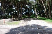 This is a picture of campsite 21 looking from the road into the partly sunny site.  This site has 50amp service and water hookups.  There is a gravel foundation with a picnic table and a ground campfire ring.