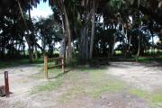 This is a picture of campsite 22 looking from the road into the partly sunny site.  This site has 50amp service and water hookups.  There is a gravel foundation with a picnic table and a ground campfire ring.