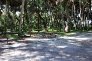 This is a picture of campsite 23 looking from the road into the partly sunny tent only site.  This site has 50amp service and water hookups.  There is a gravel foundation with a picnic table and a ground campfire ring.