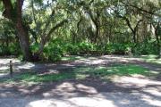 This is a picture of campsite 26 looking from the road into the shady tent only site.  This site has 50amp service and water hookups.  There is a gravel foundation with a picnic table and a ground campfire ring.