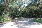 Campsite 28 is a partial sunny site with a gravel foundation located on the right hand side of the road.  Looking into the site on the right is the water and 50amp electrical service. There is a picnic table and ground campfire ring.  At the front left side of the site is the brown site marker.