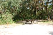 Campsite 37 is a partial sunny site with a gravel foundation located on the right hand side of the road.  Looking into the site on the right is the water and 50amp electrical service. There is a picnic table and ground campfire ring.  At the front left side of the site is the brown site marker.