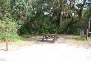 This is a picture of campsite 37 looking from the road into the partly sunny site.  This site has 50amp service and water hookups.  There is a gravel foundation with a picnic table and a ground campfire ring.