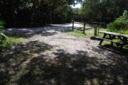 This is a picture of campsite 39 from the back of the site looking toward the road.   The site has water and 50amp electric service.  This is a sunny site with a gravel foundation.  The site has a picnic table and a ground campfire ring.