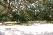 Campsite 46 is a partial sunny site with a gravel foundation located on the right hand side of the road.  Looking into the site on the right is the water and 50amp electrical service. There is a picnic table and ground campfire ring.  At the front left side of the site is the brown site marker.