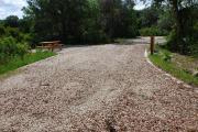 This is picture of campsite #50 from the back of the site looking toward the road.  This is a pull through site.  Site has 50amp electric, water and sewage hook-ups.  This is a sunny site with stone foundation and vegetation on sides.  There is a separate section to the side with the picnic table, cooking grill and ground campfire ring.