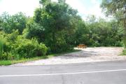 This picture of campsite #53 is looking from the road into the partial shady site.  This site has 50 amp electric, water and sewer hook-ups. There is a stone foundation with vegetation on the sides.  There is also a separate area to the side with a picnic table, cooking grill and ground campfire ring.