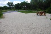 This is picture of campsite #55 from the back of the site looking toward the road.  Site has 50amp electric, water and sewage hook-ups.  This is a sunny site with stone foundation and vegetation on sides.  There is a separate section to the side with the picnic table, cooking grill and ground campfire ring.
