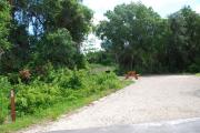 This picture of campsite #59 is looking from the road into the sunny site.  This site has 50 amp electric, water and sewer hook-ups. There is a stone foundation with vegetation on the sides.  There is also a separate area to the side with a picnic table, cooking grill and ground campfire ring.