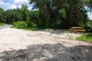 This is picture of campsite #69 from the back of the site looking toward the road.  Site has 50amp electric, water and sewage hook-ups.  This is a partial shady site with stone foundation and vegetation on sides.  There is a separate section to the side with the picnic table, cooking grill and ground campfire ring.