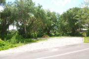 This picture of campsite #69 is looking from the road into the partial shady site.  This site has 50 amp electric, water and sewer hook-ups. There is a stone foundation with vegetation on the sides.  There is also a separate area to the side with a picnic table, cooking grill and ground campfire ring.