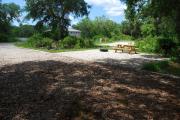 This is picture of campsite #73 from the back of the site looking toward the road.  Site has 50amp electric, water and sewage hook-ups.  This is a partial shady site with stone foundation and vegetation on sides.  There is a separate section to the side with the picnic table, cooking grill and ground campfire ring.