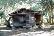 This is a front view picture of Cabin 3 which is a rustic palm log cabin built by the Civilian Conservation Corp. in the mid 1930âs.  There is a living/dining/bedroom area with 2 double beds, a sofa bed, dining set, linen cabinet and fireplace.  There also is a bathroom and a kitchen with coffee maker, toaster, microwave, range, refrigerator, dishes, silverware and cooking utensils.  The cabins sleep up to six.  Off of the back porch there is a fire ring, cooking grill and a picnic table.  There are no pets and no smoking allowed in the cabins.