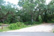 This picture of campsite #77 is looking from the road into the partial shady site.  This site has 50 amp electric, water and sewer hook-ups. There is a stone foundation with vegetation on the sides.  There is also a separate area to the side with a picnic table, cooking grill and ground campfire ring.