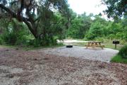 This is picture of campsite #78 from the back of the site looking toward the road.  Site has 50amp electric, water and sewage hook-ups.  This is a partial shady site with stone foundation and vegetation on sides.  There is a separate section to the side with the picnic table, cooking grill and ground campfire ring.