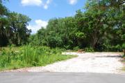 This picture of campsite #80 is looking from the road into the sunny site.  This site has 50 amp electric, water and sewer hook-ups. There is a stone foundation with vegetation on the sides.  There is also a separate area to the side with a picnic table, cooking grill and ground campfire ring.