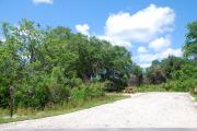 This picture of campsite #86 is looking from the road into the sunny site.  This site has 50 amp electric, water and sewer hook-ups. There is a stone foundation with vegetation on the sides.  There is also a separate area to the side with a picnic table, cooking grill and ground campfire ring.