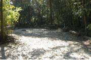 This view is from the front of the site looking in.  The water and electric hookups are on the right, the picnic table and ground grill are on the left,  This site is surrounded by mixed hardwood trees and shrubs.  The site boundaries are defined with logs.
