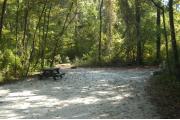 This view is from the entrance looking straight in.  The water and electric hookups are on the right, a picnic table and ground grill are on the left.  The site is surrounded by mixed hardwood trees and shrubs.  A trail leads out of the back of the site to the restrooms.
