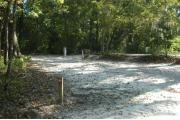 This view is from the left of the entrance with site marker #43 showing.  This is a back-in site that can accommodate campers up to 30 feet in length.  This site is located at the top of a hill. The view shows the water and electric hookups on the right side of the site with low growing shrubs between this site and #44.