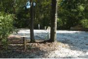 This view is from the left of the entrance with site marker #44 showing. This is a back-in site that can accommodate campers up to 42 feet in length. View shows the water and electric hookups on the right and the corner of the picnic table on the left.  The site is heavily wooded on the right and back of the site.