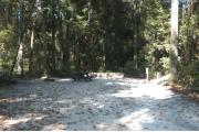 This view is from the entrance looking in.  The water and electric hookups are on the right, a picnic table and ground grill are on the left.  The back of the site is heavily wooded with mixed hardwoods trees and shrubs.  A trail leads out the back of the site to the restrooms.  Hardwood trees and low growing shrubs are on either side.