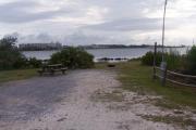 Pine trees line the sides of a well formed campsite extending to the bay.
