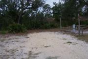 Sign post five is located to the right. Sign post connect to another post with a clothes line tied between them. Electrical post and water spigot are located to the right of the post. Near the picnic table there is a fire ring for campfires or BBQs.