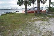 Tall pines leave an opening where the saw grass and Saw Palmettos greet the lagoon. In the distance across the water the Marriott Hotels stand quietly.