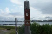 Sign post eight is located to the right. Sign post connect to another post with a clothes line tied between them. Electrical post and water spigot are located to the right of the post.
