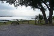 A picnic table and fire pit sits to the left next to the waters edge.