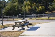 To the left sit a picnic table, fire pit and an accessible BBQ placed on a nice level concrete pad.