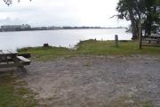A picnic table sits to the left near an opening in the grass. With low tide the lagoon waters have stepped back.