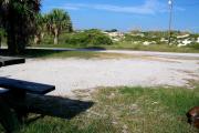View from the back showing the picnic table and fire ring in the foreground and dunes across the street from the site.