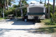 View from the front showing the RV hooked up to the water and electric on the right and picnic table on the left.