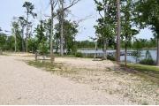 A picnic table and ground grill with electric and water in a campsite with view of pier of Lake Seminole.