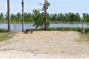 A picnic table and ground grill with electric and water in a campsite with view of lake.