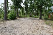 A picnic table and ground grill with electric and water in a campsite with view of cabin.